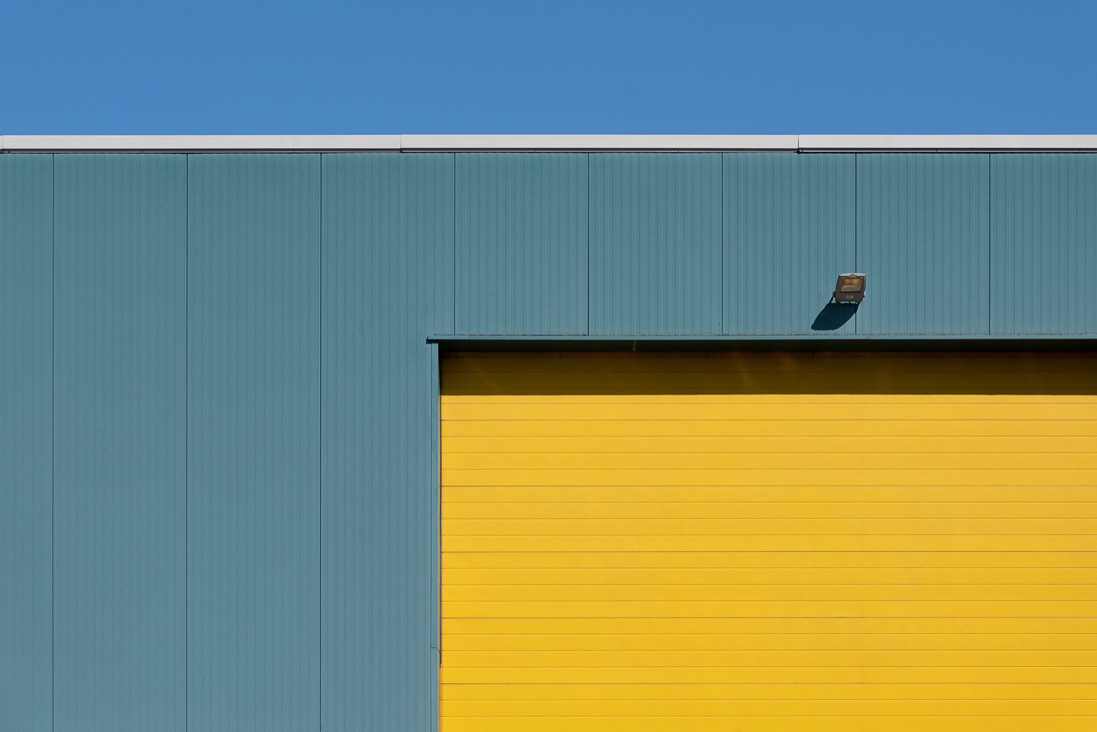 Metal-clad industrial building exterior with a yellow overhead door