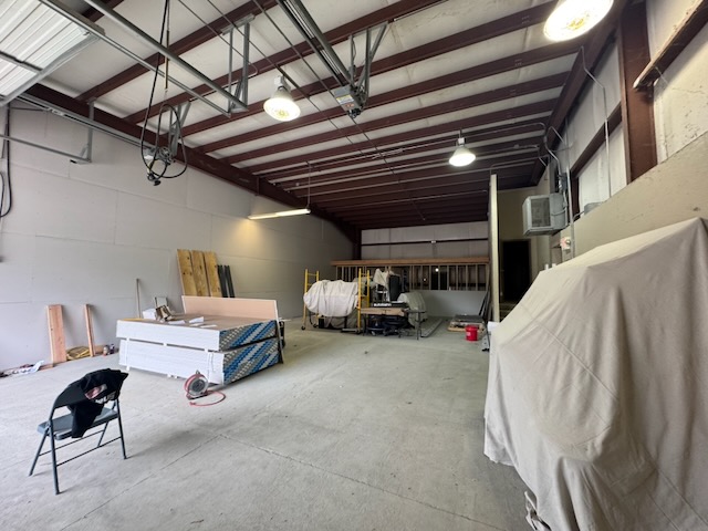 Bay 3 interior with tools staged and equipment covered, mezzanine framing visible in the background